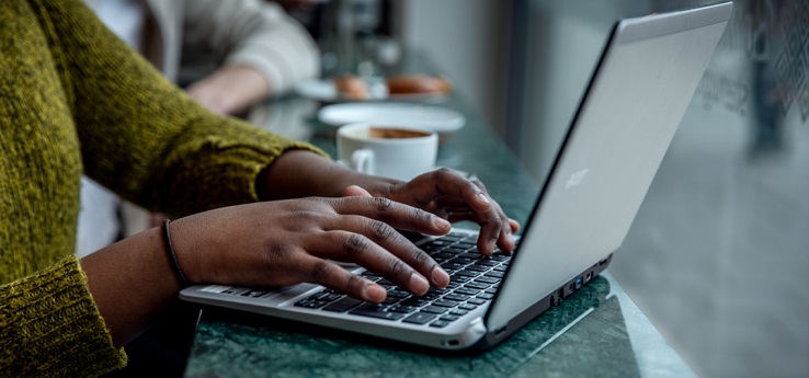 En bärbar dator och en kvinnas händer som skriver på tangentbordet.