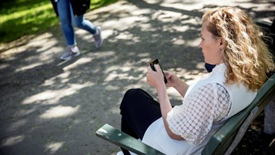 Flicka  bakifrån sittandes på en parkbänk