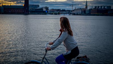 Flicka på cykel på bro vid  vatten