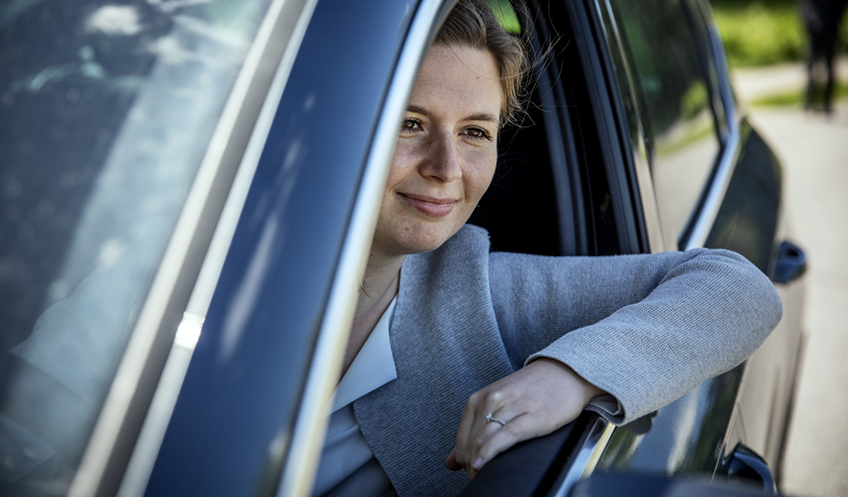 Mathilda Janson sitter i en bil och tittar ut genom den öppna bildrutan.