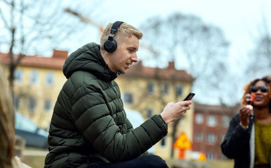 Man sitting outside with headphones and smartphone